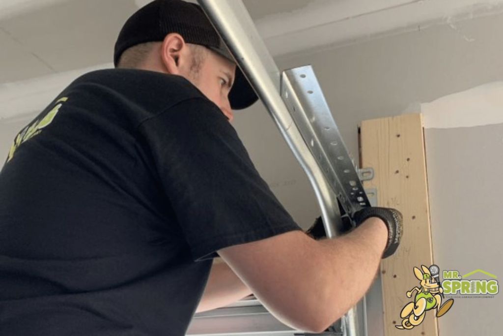Technician repairing a garage door track