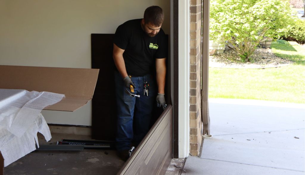 technician uses a hammer to adjust a new garage door panel