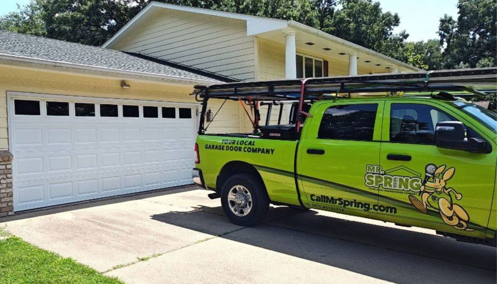 bright green Mr. Spring pickup truck sits in driveway of house in front of new white garage door