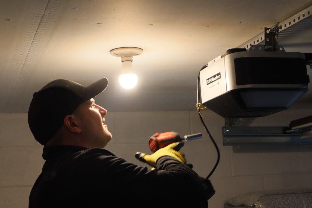 garage door technician looking at a liftmaster garage door opener under a lightbulb