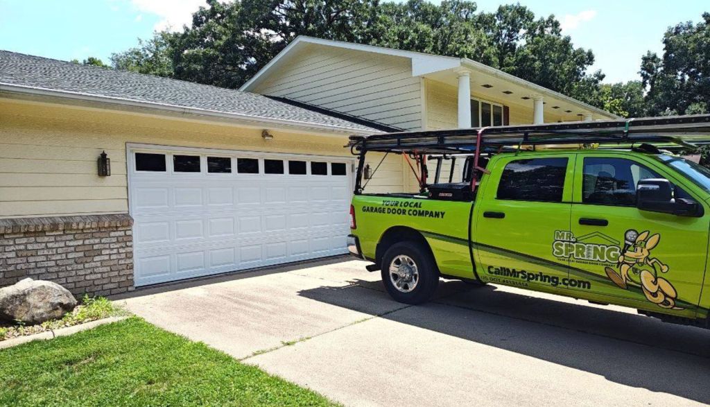 bright green Mr. Spring pickup truck sits in a driveway in front of a new white garage door