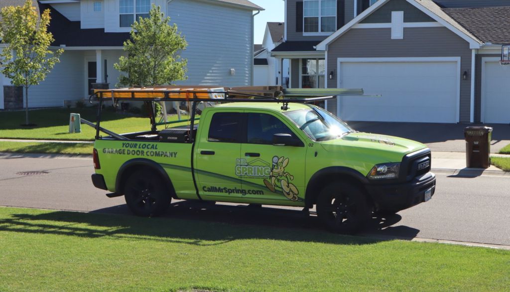 bright green Mr. Spring pickup truck sits on a suburban street in front of a garage door