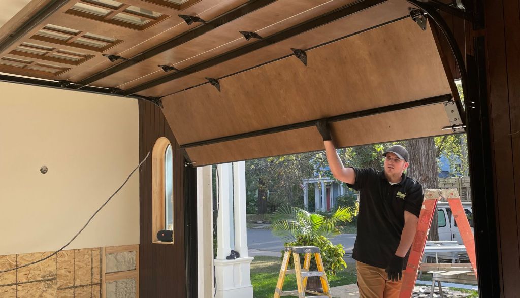 a Mr. Spring technician holds up a partially open garage door as they test it