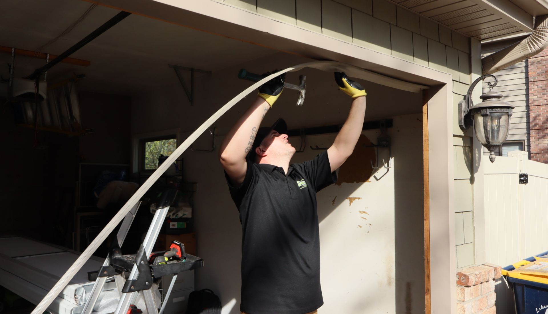 Mr. Spring technician reaches overhead to hammer new trim to the top of an open garage door frame