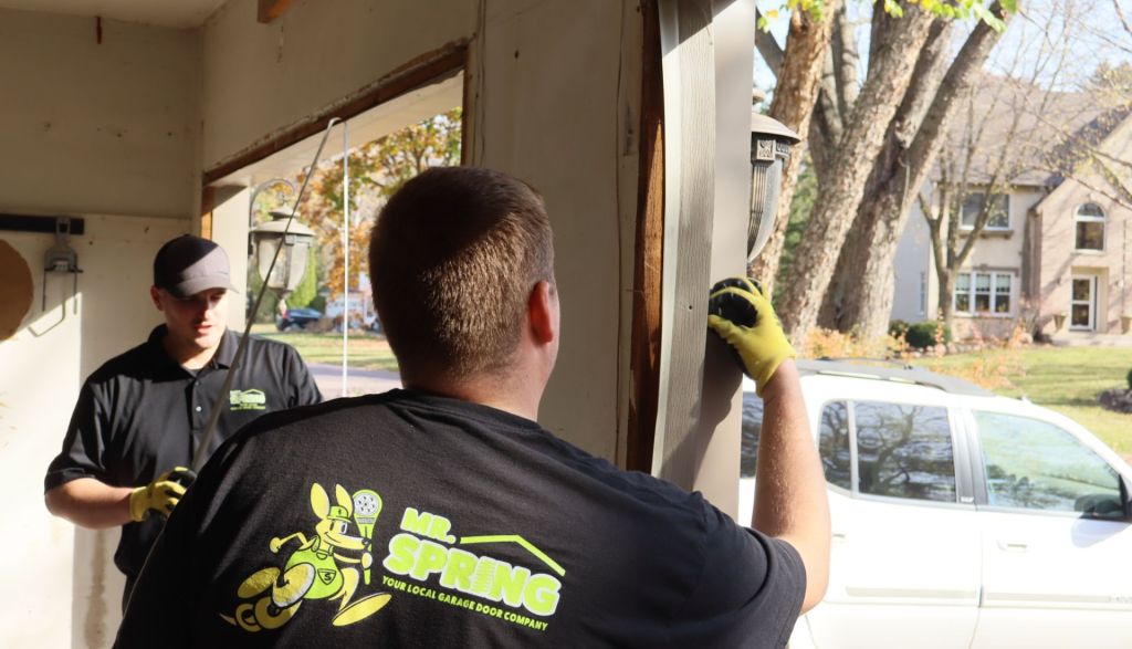 two mr. spring technicians installing trim for a garage door