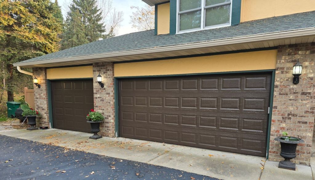 two new brown double wide garage doors with stone pillars on either side