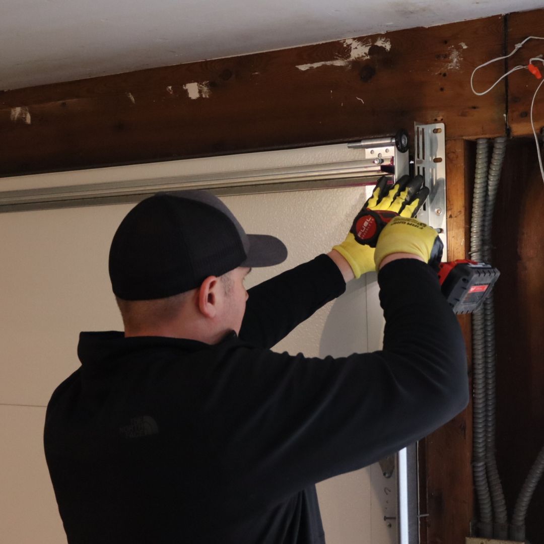 A Mr. Spring tech working on garage door tracks using an impact driver
