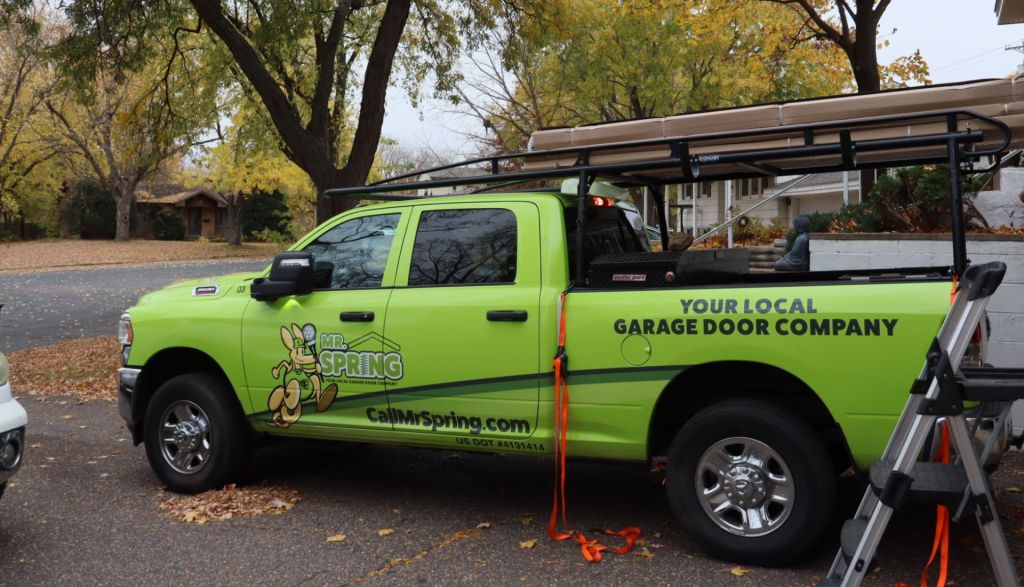 Bright green Mr. Spring pickup truck sits in a suburban driveway in the fall